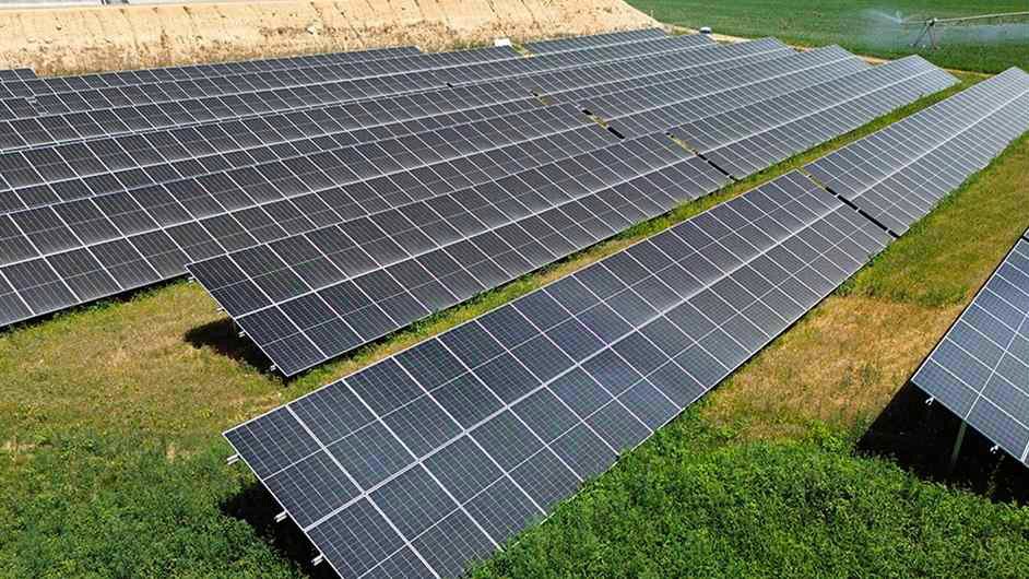 Filas de paneles solares sobre la hierba de una planta fotovoltaica, vistas desde lo alto