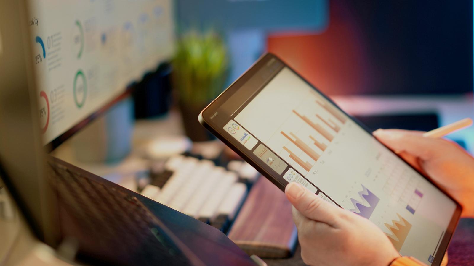 Manos sosteniendo una tableta con un cuadro de mando de datos